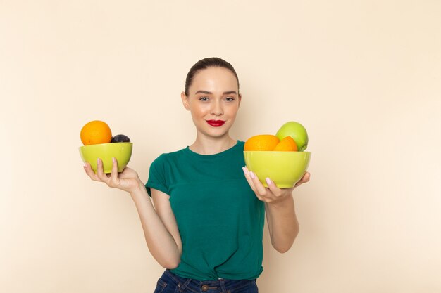 Vooraanzicht jong aantrekkelijk wijfje in de donkergroene platen van de overhemdsholding met fruit