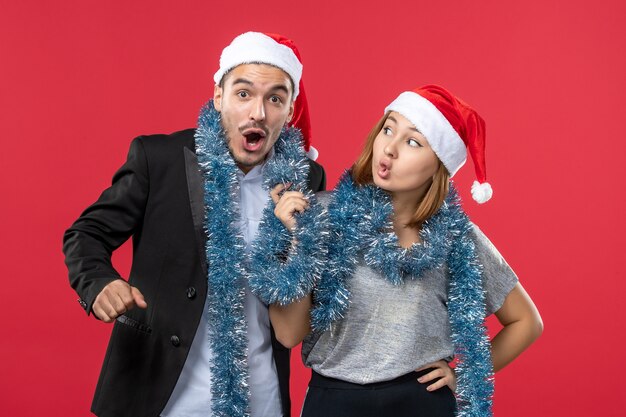 Vooraanzicht jong gelukkig paar in nieuwe jaarsfeer op de rode muurkleur Kerstmisliefde