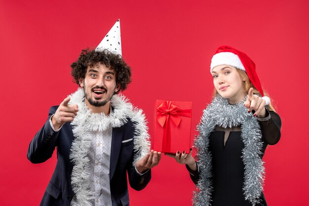 Vooraanzicht jong koppel met nieuw jaar aanwezig op de rode muur emotie kerst liefde