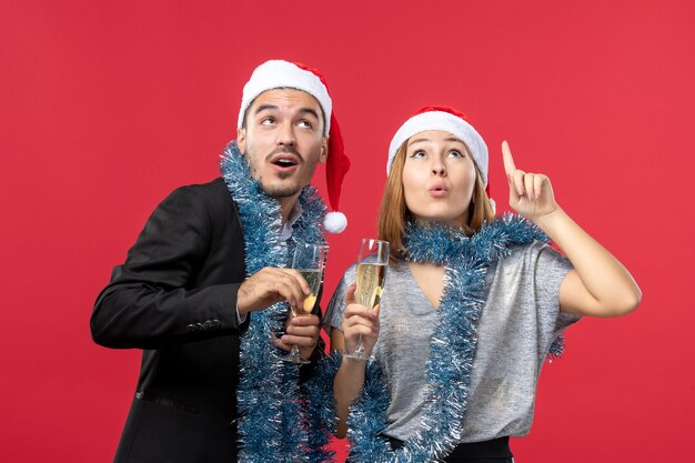 Vooraanzicht jong koppel Nieuwjaar vieren op rode muur partij Kerstmisliefde