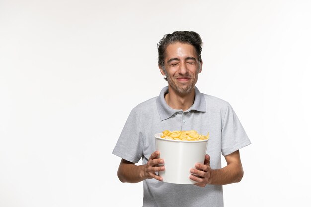 Vooraanzicht jong mannetje dat chips op wit bureau eet