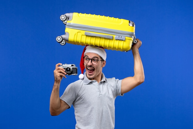 Vooraanzicht jong mannetje dat foto's neemt en zak op het vliegtuig van de de blauwe muurvlucht houdt