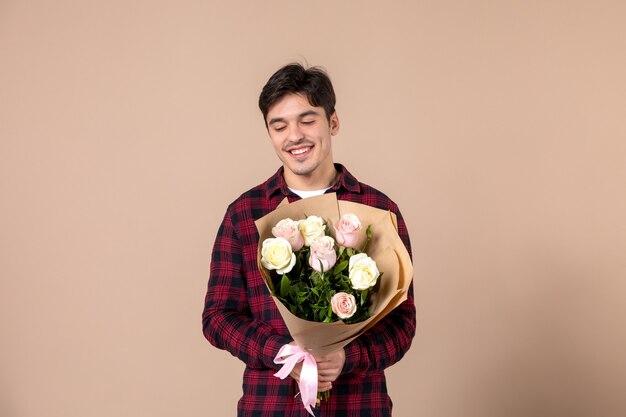 Vooraanzicht jong mannetje dat mooie bloemen op bruine muur houdt