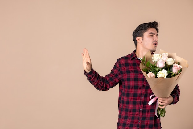 Vooraanzicht jong mannetje dat mooie bloemen op bruine muur houdt