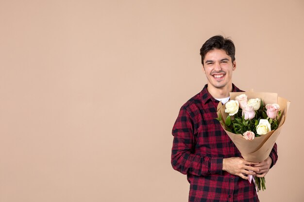 Vooraanzicht jong mannetje dat mooie bloemen op bruine muur houdt