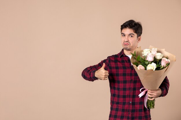 Vooraanzicht jong mannetje dat mooie bloemen op bruine muur houdt