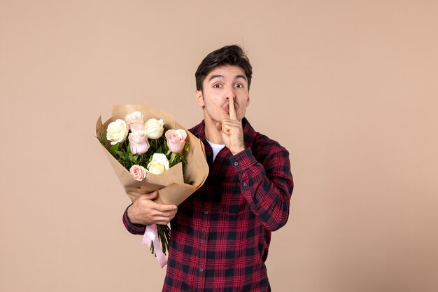 Vooraanzicht jong mannetje dat mooie bloemen op bruine muur houdt