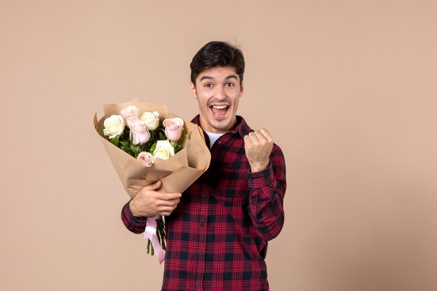 Vooraanzicht jong mannetje dat mooie bloemen op bruine muur houdt