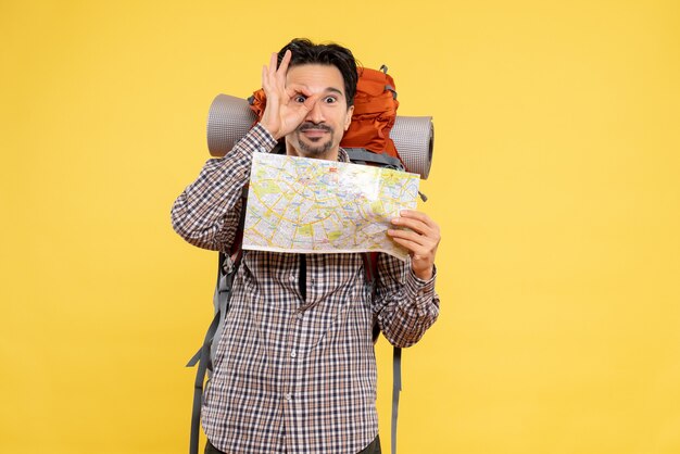 Vooraanzicht jong mannetje dat voor het wandelen met kaart voorbereidingen treft op geel