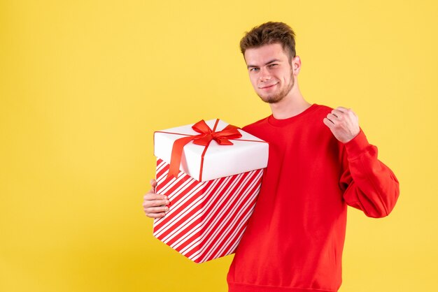 Vooraanzicht jong mannetje in rood overhemd met heden in doos