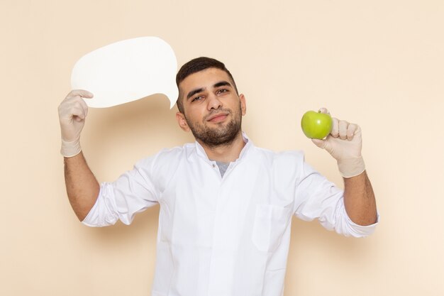 Vooraanzicht jong mannetje in wit kostuum die handschoenen dragen die wit teken en appel op beige houden