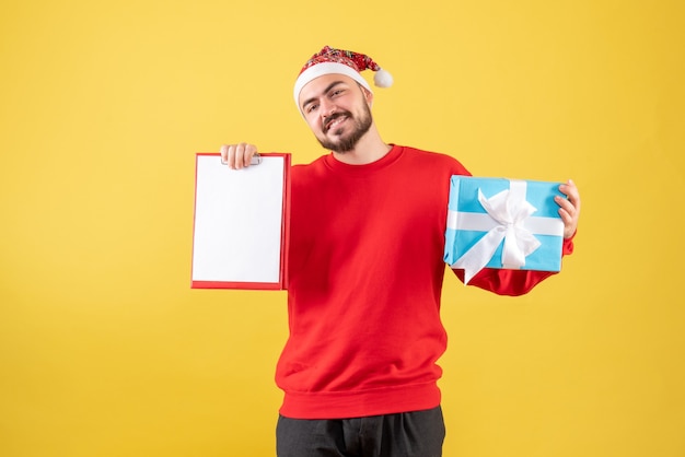 Vooraanzicht jong mannetje met aanwezige Kerstmis en nota over gele achtergrond