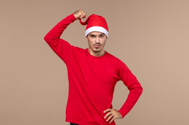 Vooraanzicht jong mannetje met rode Kerstmiskaap op bruine ruimte