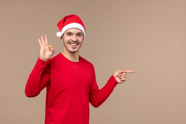 Vooraanzicht jong mannetje met rode Kerstmiskaap op bruine ruimte