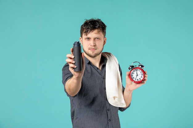 vooraanzicht jong mannetje met schuim voor het scheren en klok op blauwe achtergrond