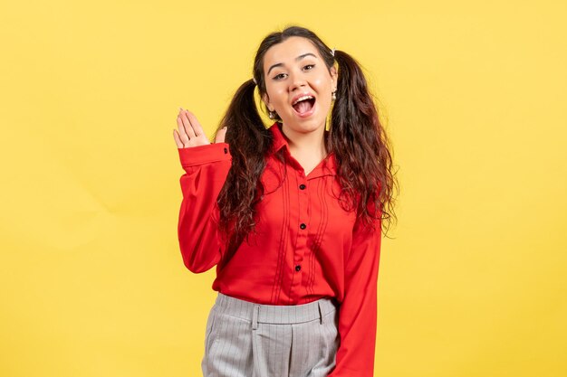 Vooraanzicht jong meisje in rode blouse met opgewonden uitdrukking op gele achtergrond vrouwelijk gevoel kind kind meisje jeugd emotie