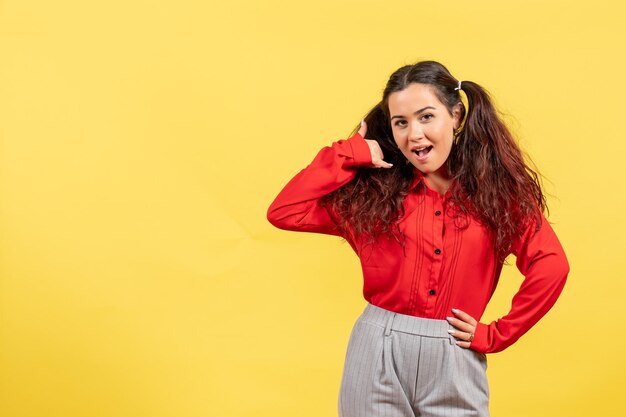 Vooraanzicht jong meisje in rode blouse met schattig haar dat gewoon op gele achtergrond staat kinderkleur kind meisje jeugd onschuld