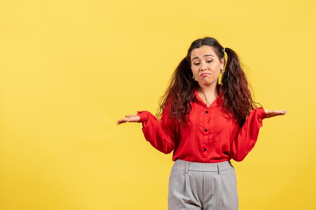 Vooraanzicht jong meisje in rode blouse met schattig haar en verward gezicht op gele achtergrond kind meisje jeugd onschuld kleur kid