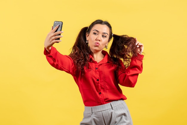 Vooraanzicht jong meisje in rode blouse met schattig haar selfie te nemen op gele achtergrond kind meisje jeugd onschuld kleuren kind