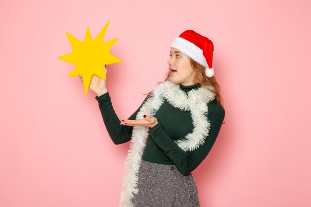 Vooraanzicht jong wijfje dat grote gele figuur op roze muurkleur model vakantie kerstmis nieuwjaar emotie houdt