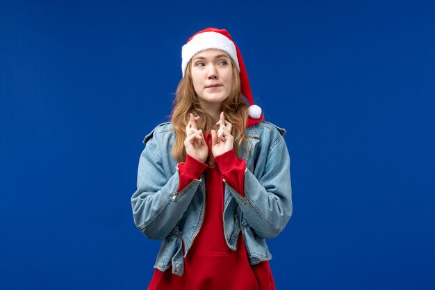 Gratis foto vooraanzicht jong wijfje die haar vingers kruisen op blauwe achtergrond nieuwe jaarvakantie kerstmis