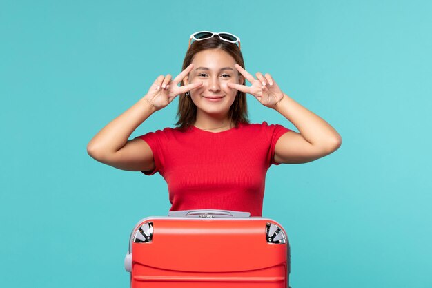 Vooraanzicht jong wijfje die met rode zak voor vakantie op blauw bureau voorbereidingen treffen