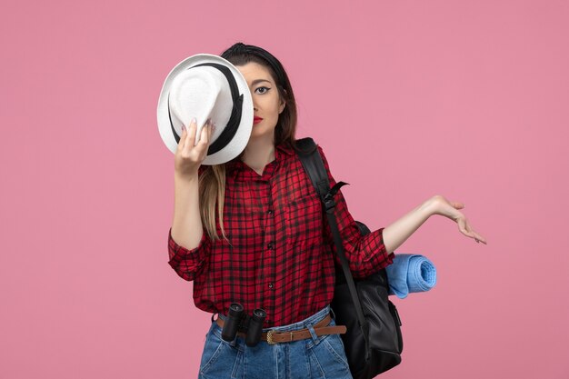 Vooraanzicht jong wijfje in rood overhemd met hoed op het roze menselijke model van de achtergrondkleurvrouw