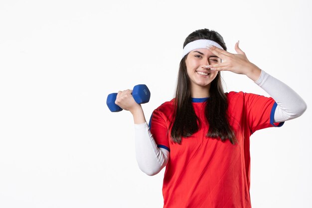 Vooraanzicht jong wijfje in sportkleren met blauwe domoren op witte muur