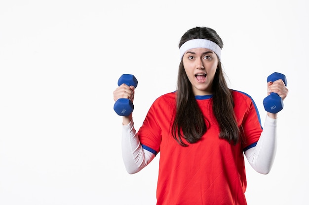 Vooraanzicht jong wijfje in sportkleren met blauwe domoren op witte muur