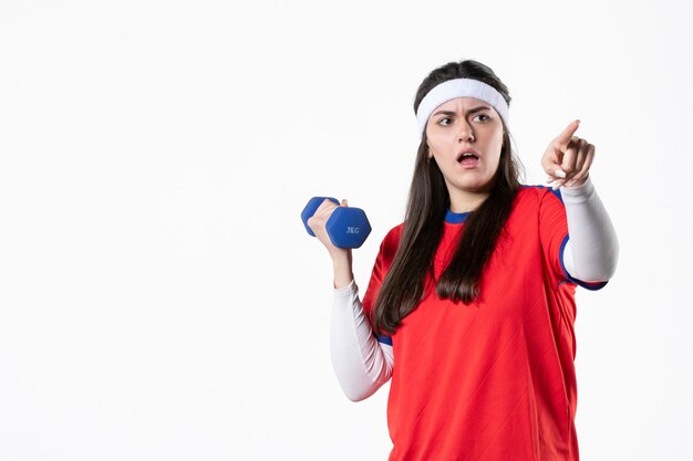 Vooraanzicht jong wijfje in sportkleren met blauwe domoren op witte muur