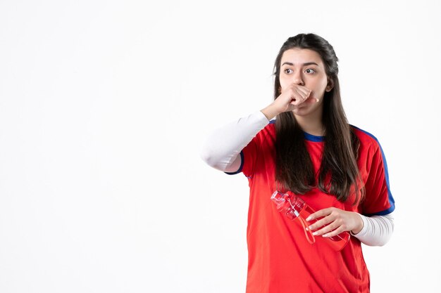 Vooraanzicht jong wijfje in sportkleren met fles water op witte muur