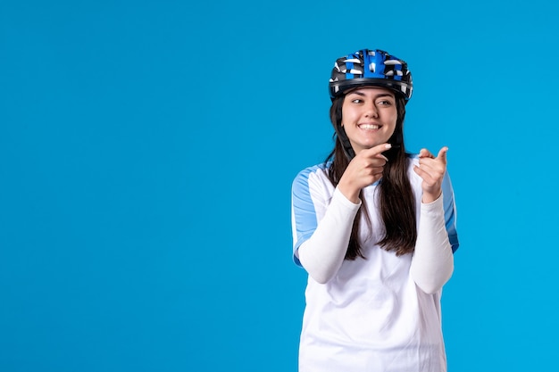 Vooraanzicht jong wijfje in sportkleren met helm op blauwe muur