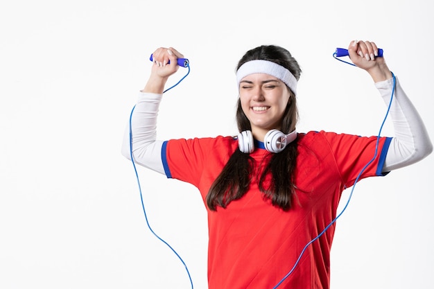 Vooraanzicht jong wijfje in sportkleren met springtouwen op witte muur