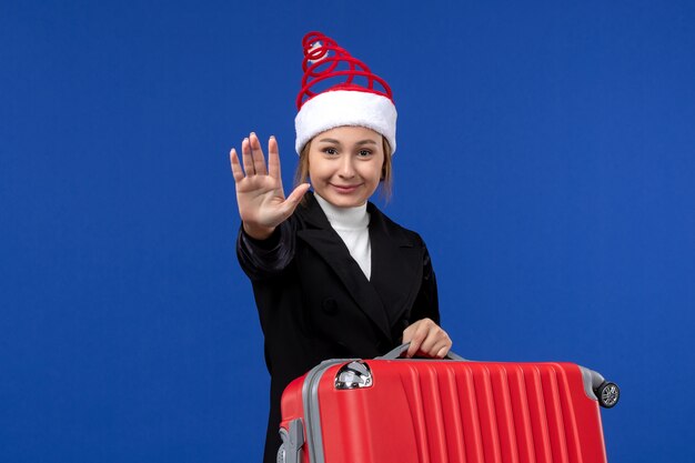 Vooraanzicht jong wijfje met grote rode zak op het vliegtuig van de de vakantievrouw van de blauwe muur