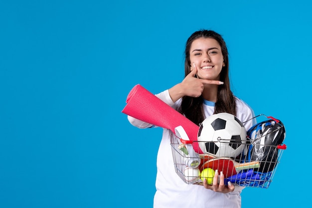 Vooraanzicht jong wijfje met mand na sport die op blauwe muur winkelen