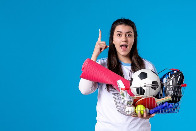 Vooraanzicht jong wijfje met mand na sport die op blauwe muur winkelen