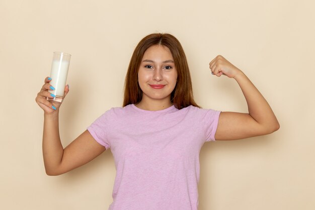 Vooraanzicht jonge aantrekkelijke vrouw in roze t-shirt en spijkerbroek met glas melk en buigen