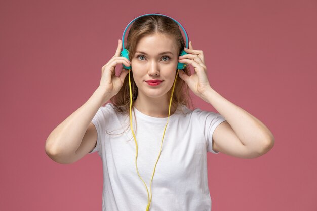 Vooraanzicht jonge aantrekkelijke vrouw luisteren naar muziek op roze muur model kleur vrouwelijke jong