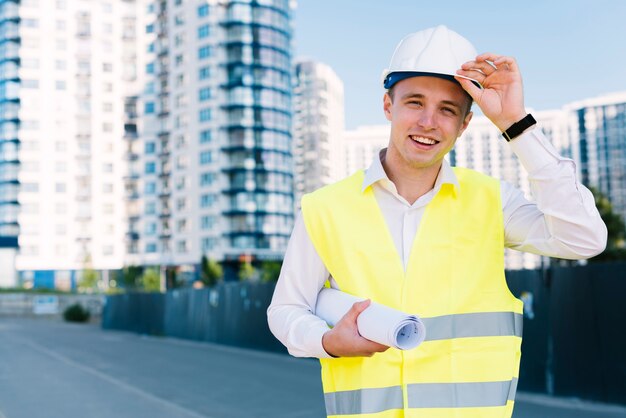 Vooraanzicht jonge architect met plannen en helm