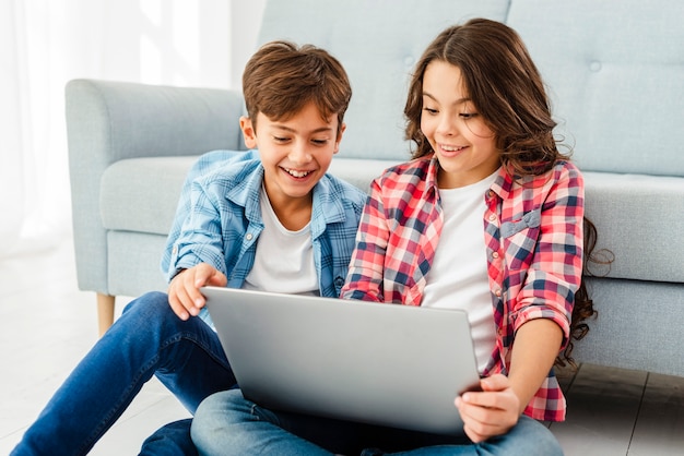 Gratis foto vooraanzicht jonge broers en zussen met laptop