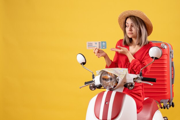 Vooraanzicht jonge dame in rode jurk en panamahoed met kaartje op bromfiets