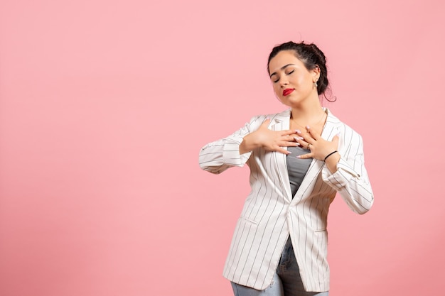 Vooraanzicht jonge dame in witte jas met dromend gezicht op roze achtergrond mode vrouw emotie kleur gevoel dame