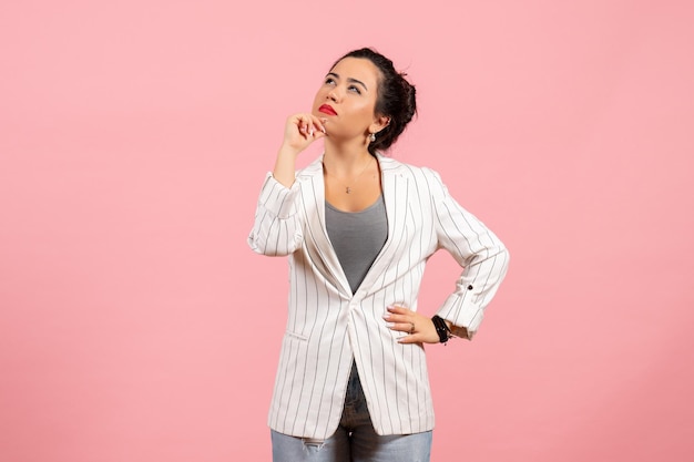 Vooraanzicht jonge dame met witte jas poseren en denken op roze achtergrond dame emoties mode vrouw kleur gevoel