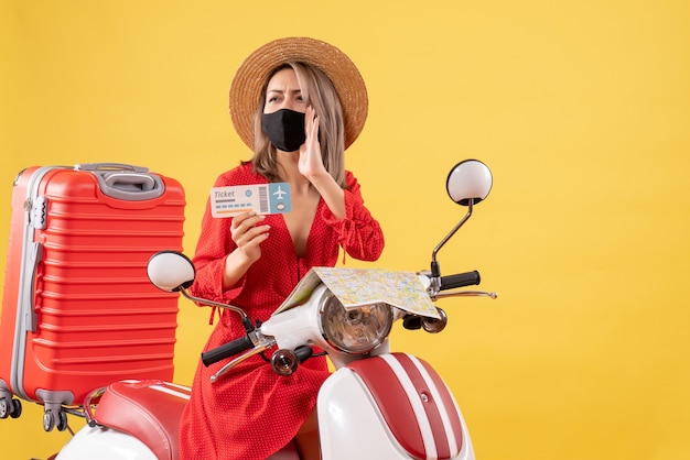 Vooraanzicht jonge dame met zwart masker op bromfiets met ticket dat iemand belt calling