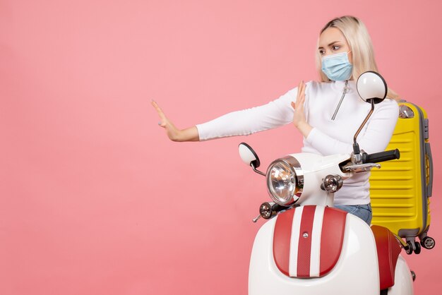 Vooraanzicht jonge dame op bromfiets met gele koffer stopbord maken