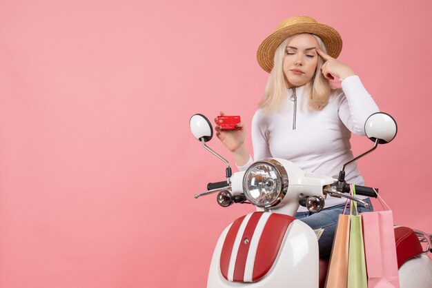 Vooraanzicht jonge dame op de creditcard van de bromfietsholding