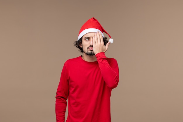 Vooraanzicht jonge man die de helft van zijn gezicht op een bruine achtergrond emotie kerstvakantie