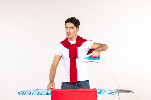 Vooraanzicht jonge man die zich voorbereidt om de handdoek op een witte achtergrond te strijken schoon huishoudelijk werk thuiswerk emotie mode kleding man