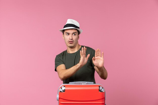 Vooraanzicht jonge man die zich voorbereidt op vakantie met hoed op roze ruimte