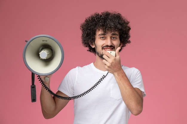 Gratis foto vooraanzicht jonge man glimlachend en informeren met handmicrofoon